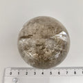 Røgkvarts Kugle 5,5 cm med regnbue. Den har små ujævnheder.